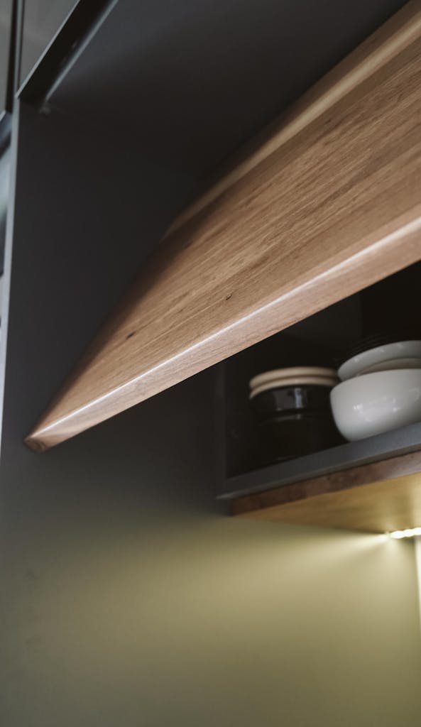 Elegant kitchen interior featuring a modern minimalist shelf with wooden accents and bowls.